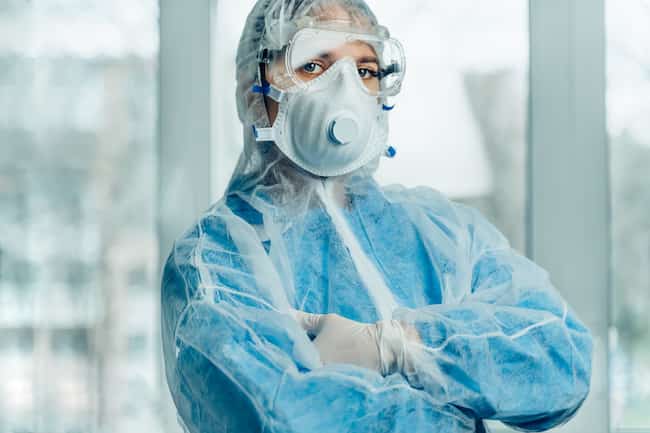 Портрет женщины-врача в защитном костюме во время пандемии коронавируса. Защитный костюм, респираторная маска, перчатки и очки в клинике или больнице. Защита от коронавируса, концепция эпидемии ковид-19.